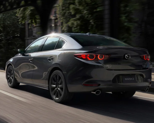 exterior view of a gray 2025 mazda driving down a dirt road showcasing performance and power