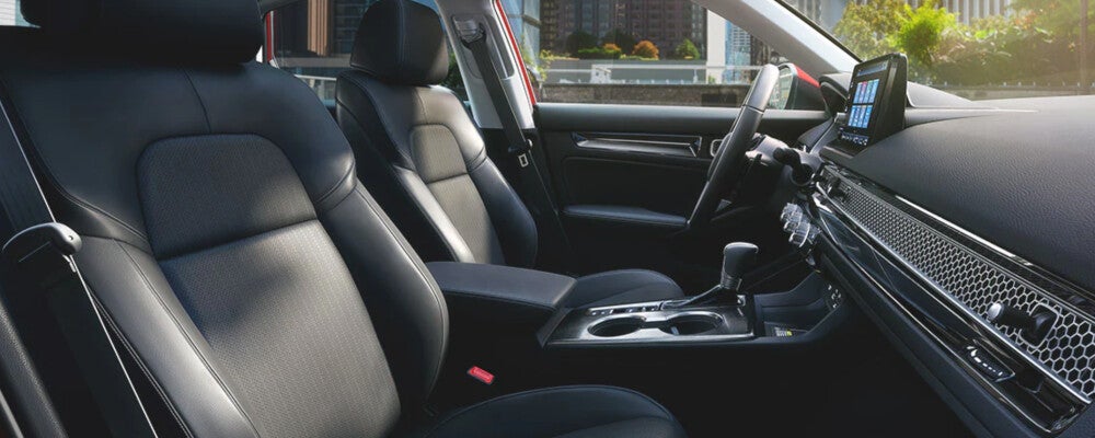 Front passenger-side view of a car interior with black leather seats, a center console, and a dashboard-mounted touchscreen.