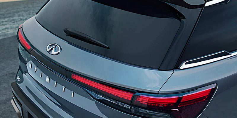 Rear view of a dark gray Infiniti QX60 car, showing the logo, "INFINITI" text, and left taillight.
