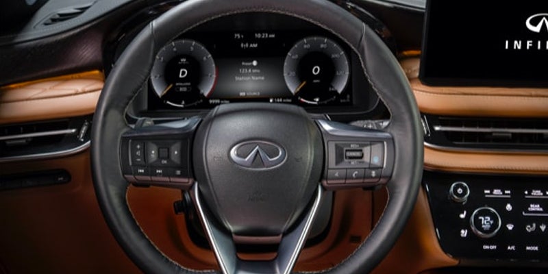 Driver's view of an Infiniti QX60 car interior, showing the steering wheel, digital dashboard.