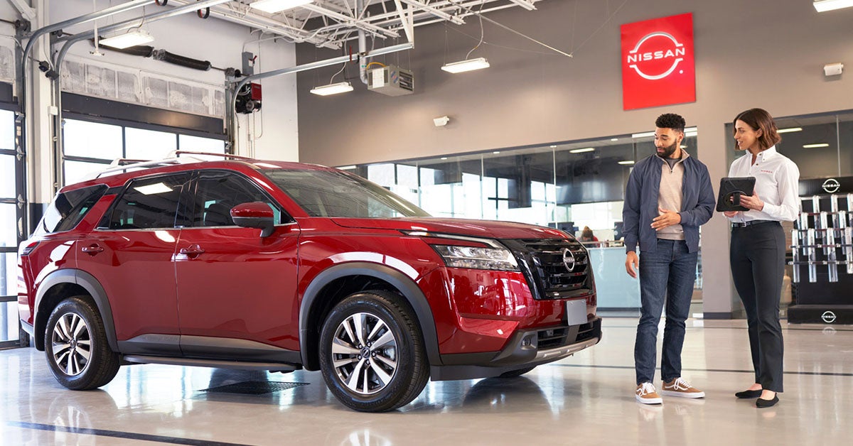 Customer and dealer in Nissan dealership by red car