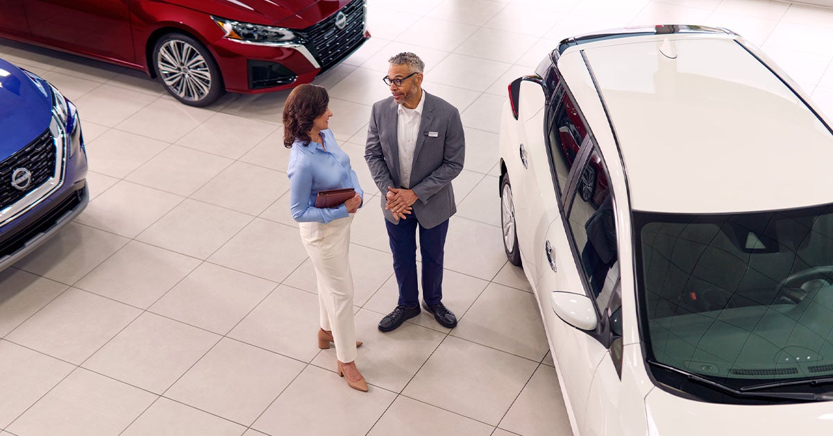 Customer and dealer in Nissan showroom by white car