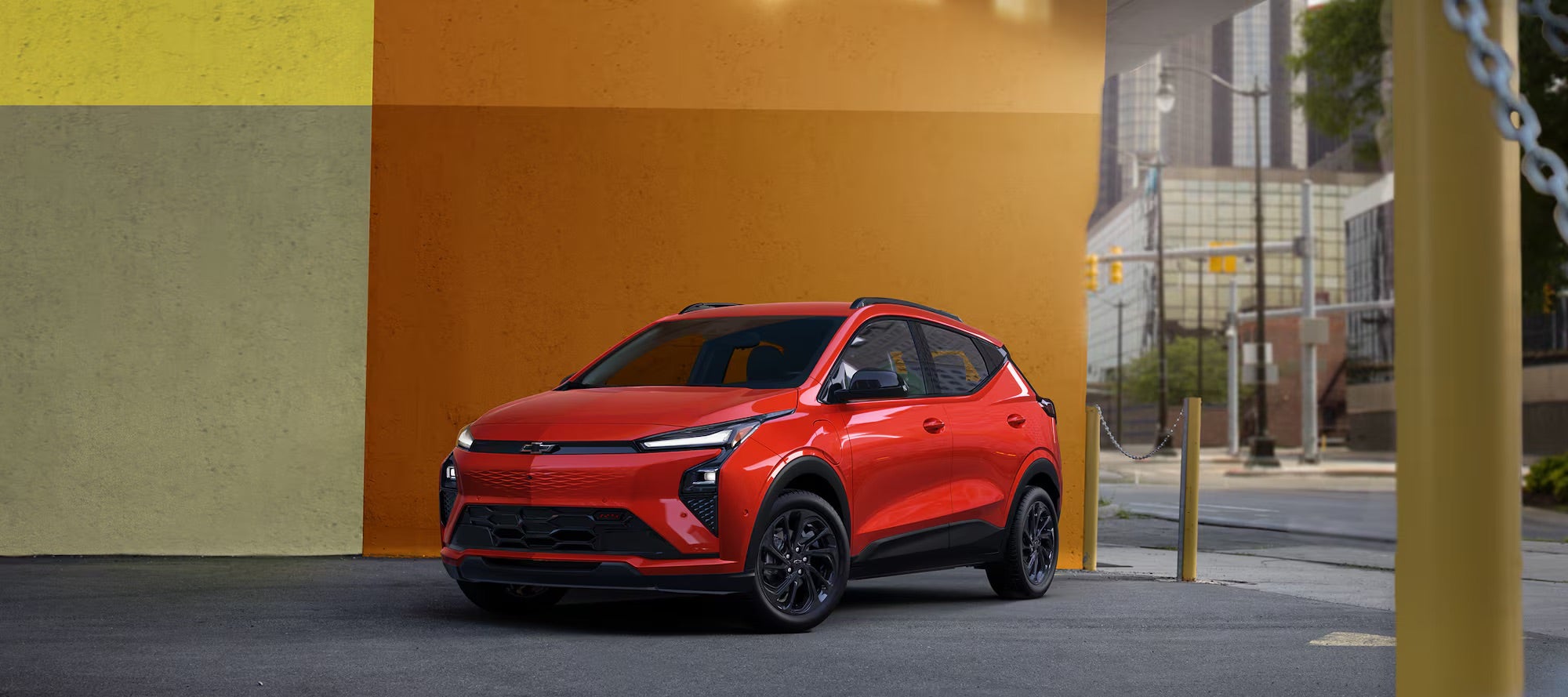 Red 2027 Chevy Bolt RS parked against a modern mural in city