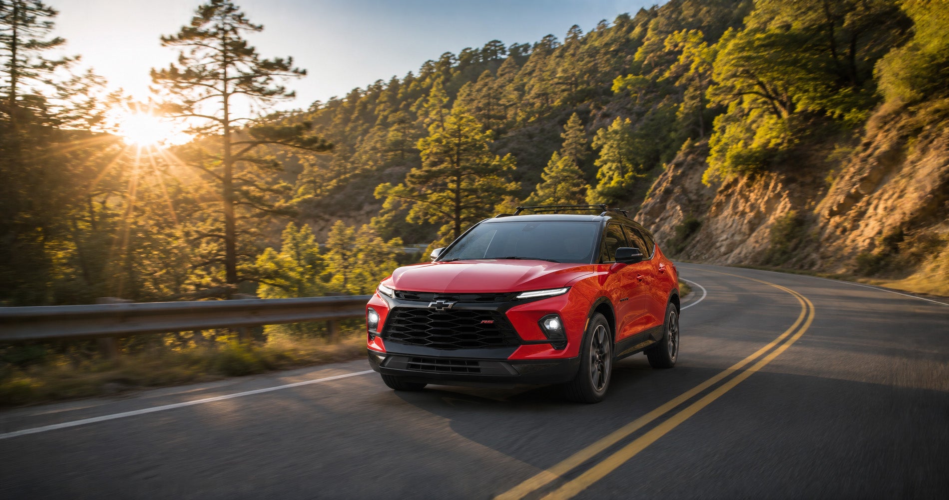 Red Blazer RS driving through winding forest road at sunrise, emphasizing sporty performance and agility.