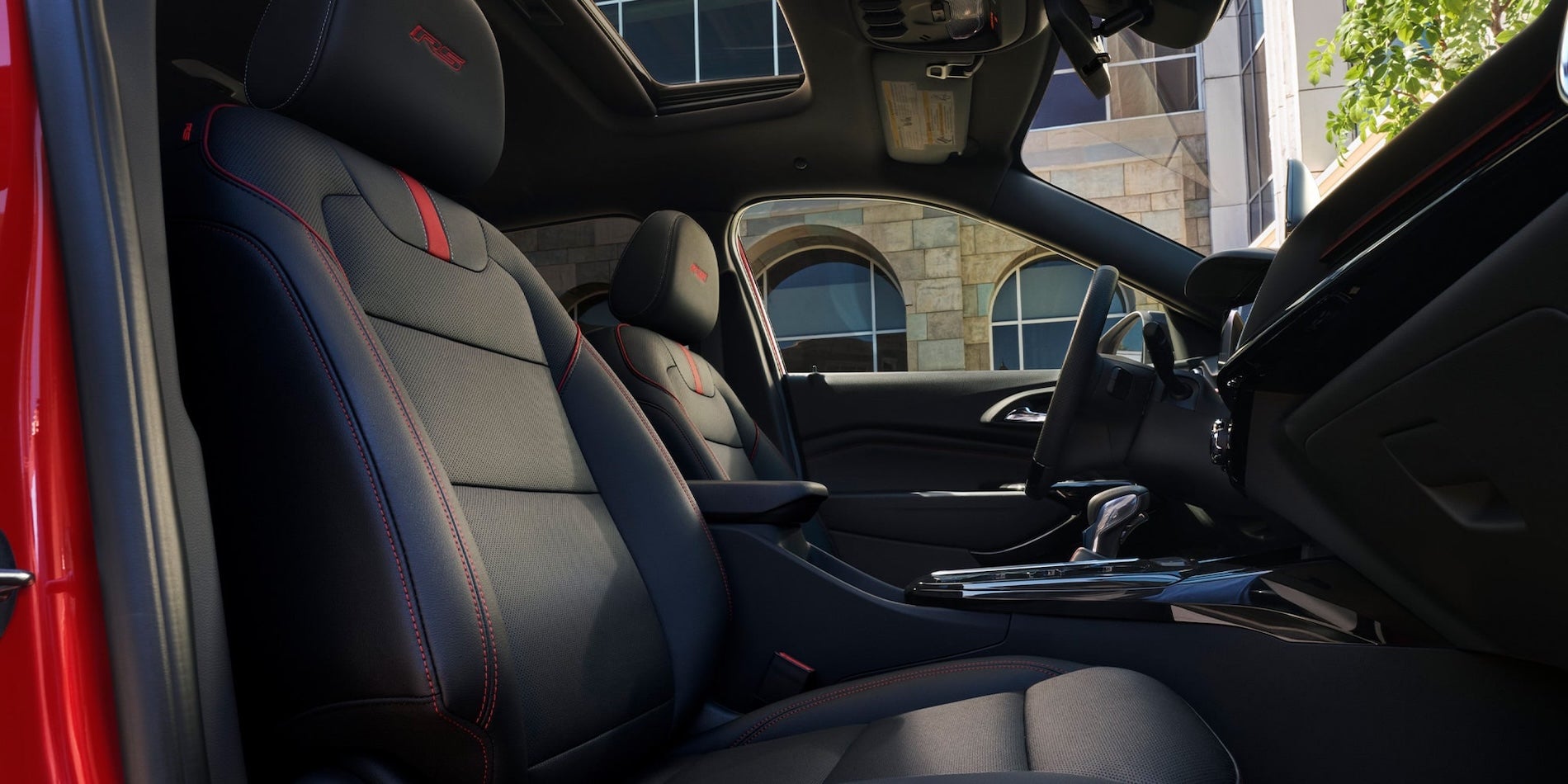 2026 Chevy Trax RS interior front seats with red stitching, center console, steering wheel, and sunroof