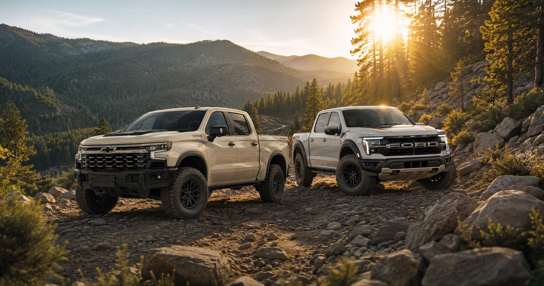 Beige Chevrolet Silverado ZR2 and Ford F-150 Raptor parked on a rocky mountain trail at sunrise, showcasing extreme off-road capability.