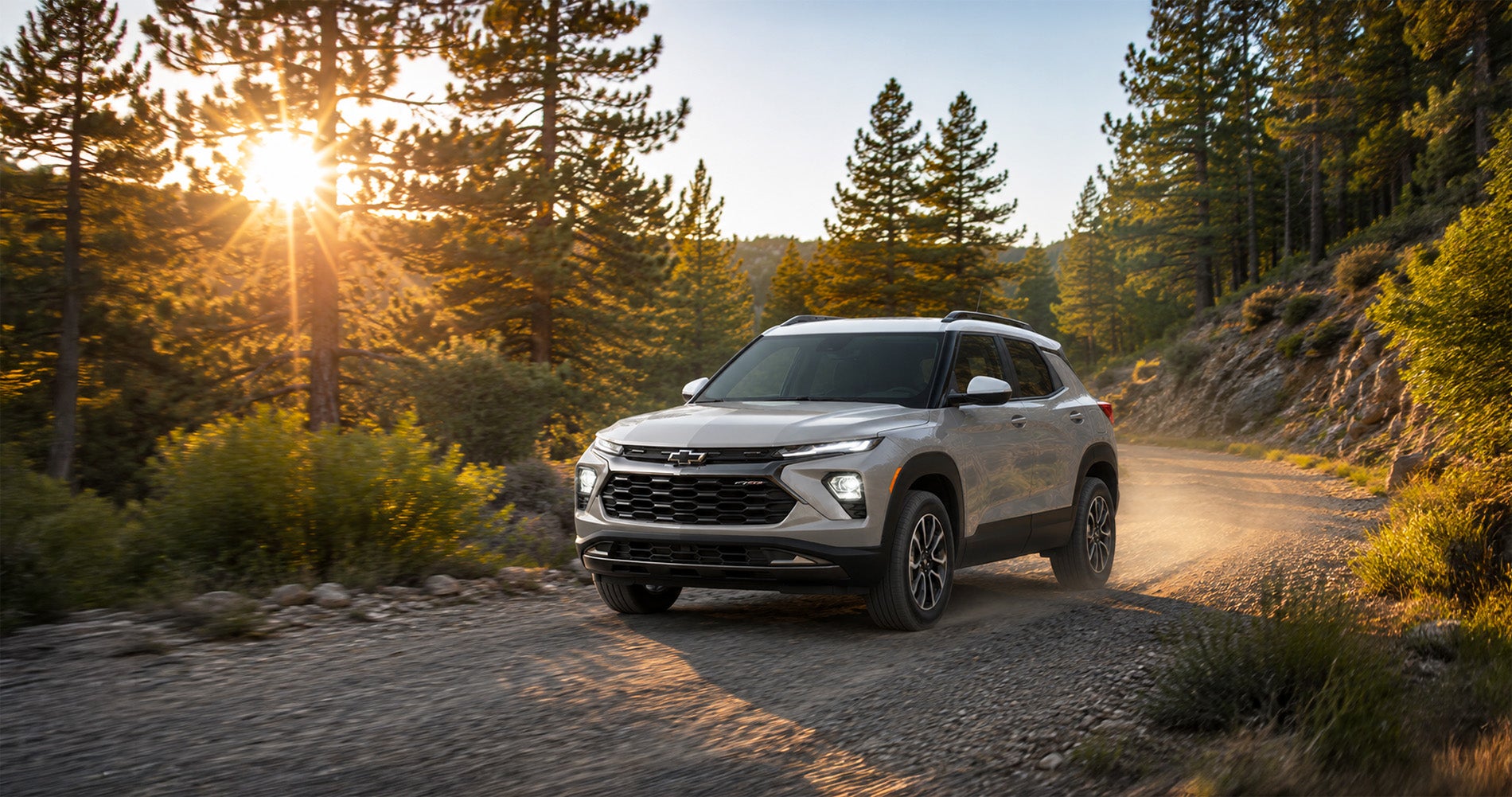 White Sands 2026 Chevrolet Trailblazer ACTIV driving on a dirt forest road, highlighting outdoor-inspired style.
