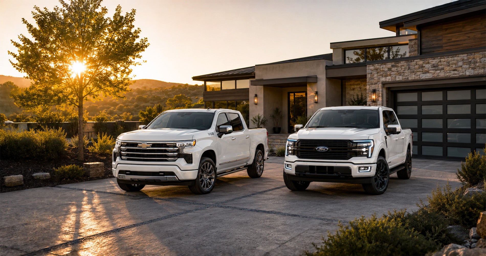 White Chevrolet Silverado High Country and Ford F-150 Platinum parked in a modern driveway at sunset, highlighting premium trims.