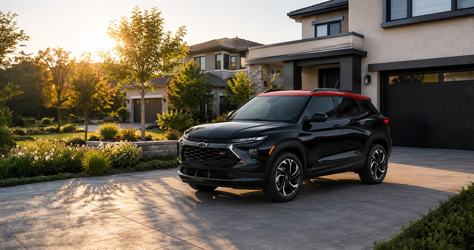 Black 2026 Chevrolet Trailblazer RS with red roof parked in a modern driveway at sunset, showcasing sporty urban design.
