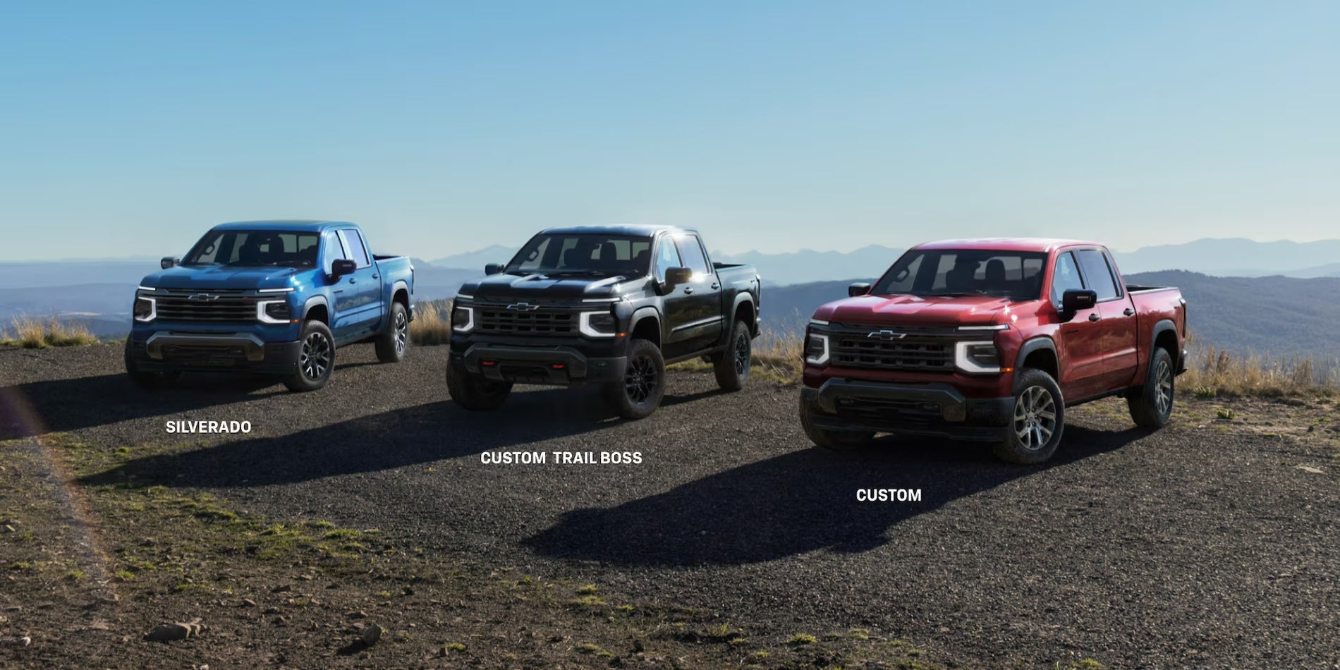 Three 2027 Chevrolet Silverado 1500 trim levels parked on a rural overlook.