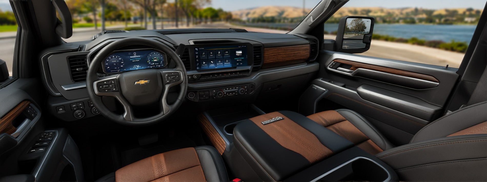 2026 Chevrolet Silverado 2500 High Country trim level interior view of black and brown leather with wood accents, with the scene as the truck parked next to a lake in a park area