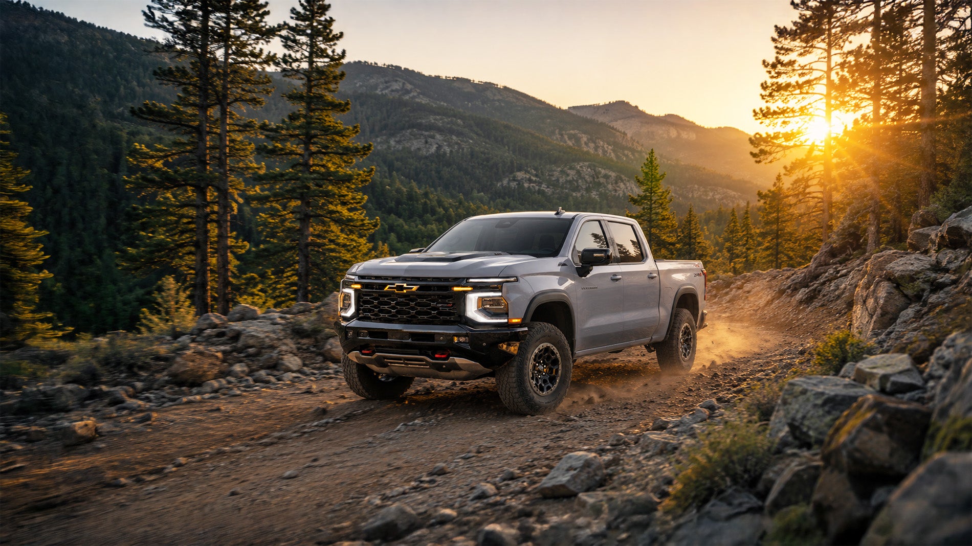 2027 Chevrolet Silverado 1500 ZR2 driving through the mountains at sunset.