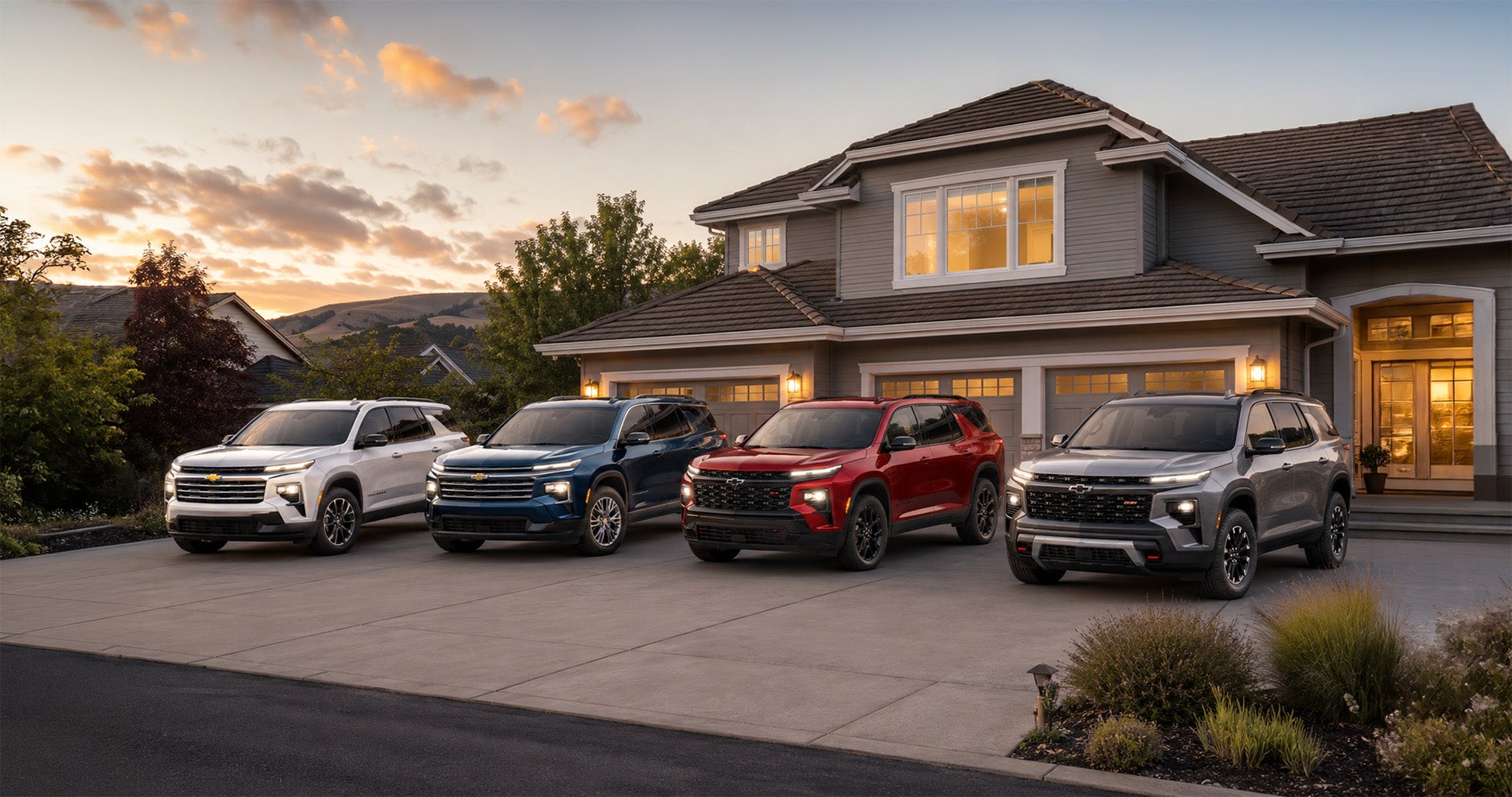 Four 2026 Chevrolet Traverse SUVs in white, blue, red, and gray parked side by side in a residential driveway at sunset, highlighting the range of Traverse trim levels available at Delta Chevrolet in Pittsburg, CA.