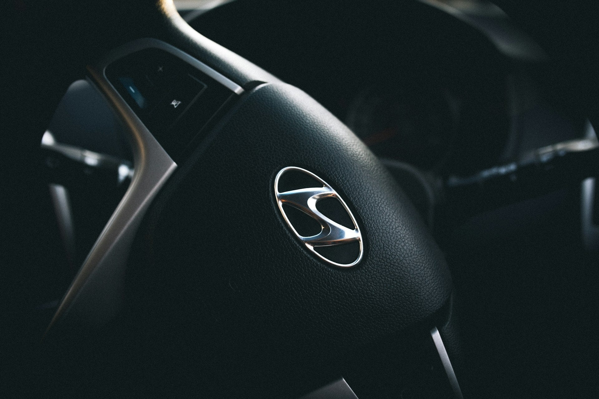The interior of a car shows a steering wheel, dashboard with digital screens, climate control, and gear shift.