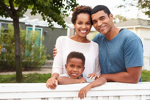 a family standing by a wooden vinyl fence around a house