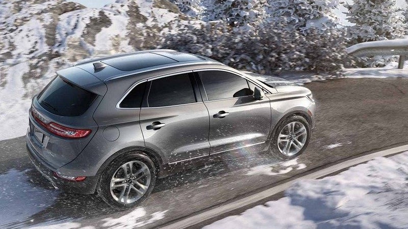 Silver Lincoln MKC SUV driving on a snowy mountain road.