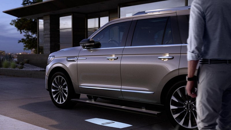 A Lincoln Navigator projecting a welcome mat logo onto the ground
