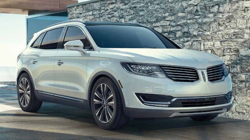 A Lincoln MKC SUV parked in front of a stone wall.
