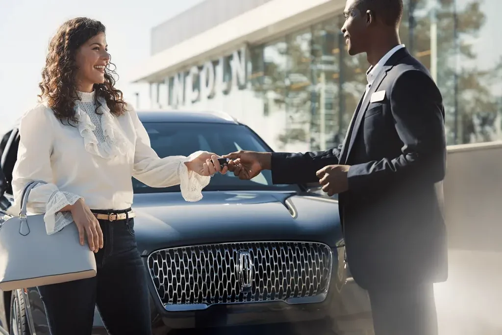 A Lincoln representative handing car keys to a smiling woman.