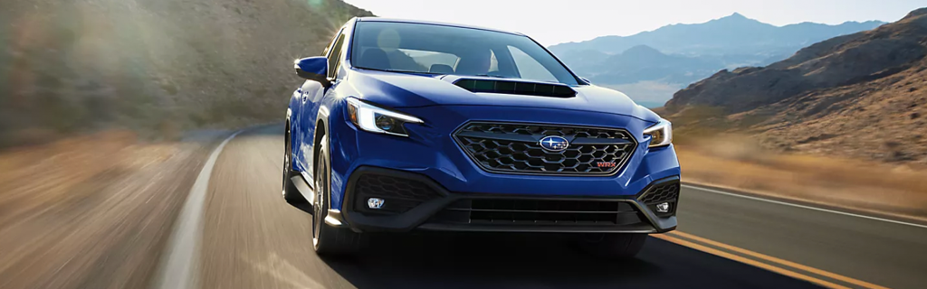 Blue Subaru WRX driving on a mountain road.