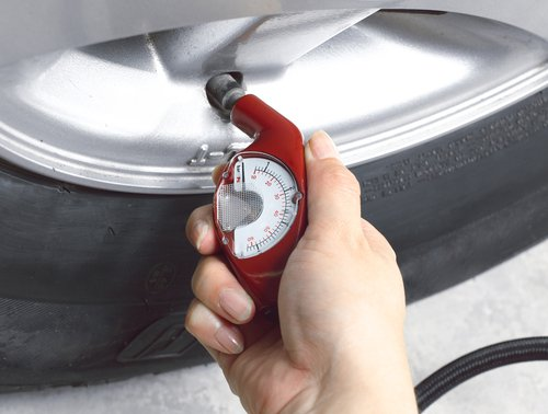 A person checking tire pressure with a gauge.