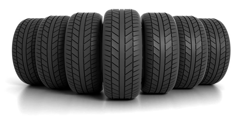 A close-up, angled view of five dark gray car tires, showing detailed tread patterns.