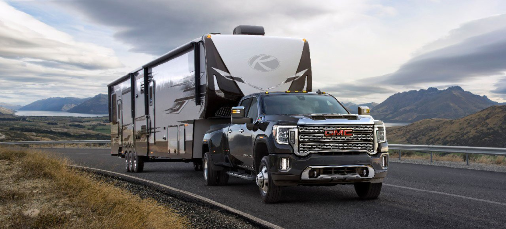 Black GMC pickup truck hauling a large tracked.