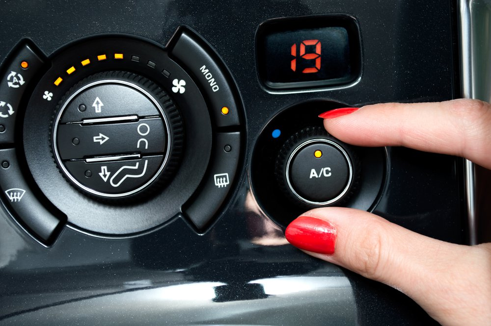 Close-up of a car dashboard with four round air vents, the rightmost with an air recirculate button.