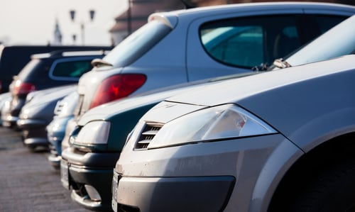 Close-up view of a row of parked cars showing rear lights and side panels