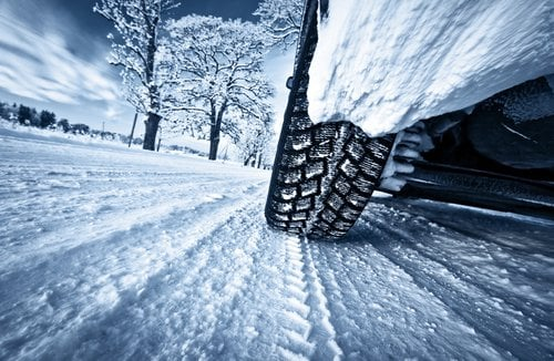 Car tire driving on snowy road.