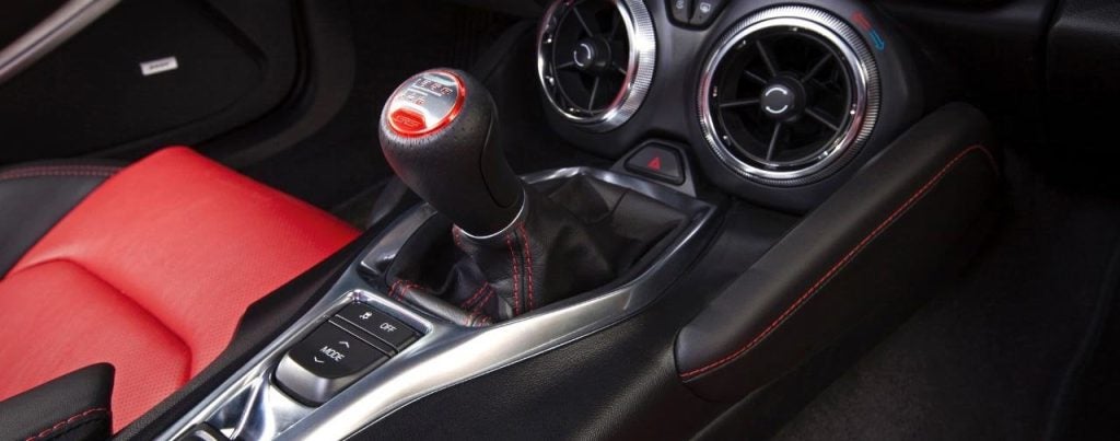 A Camaro interior with red and black leather upholstery, a 6-speed manual shifter, and air vents.