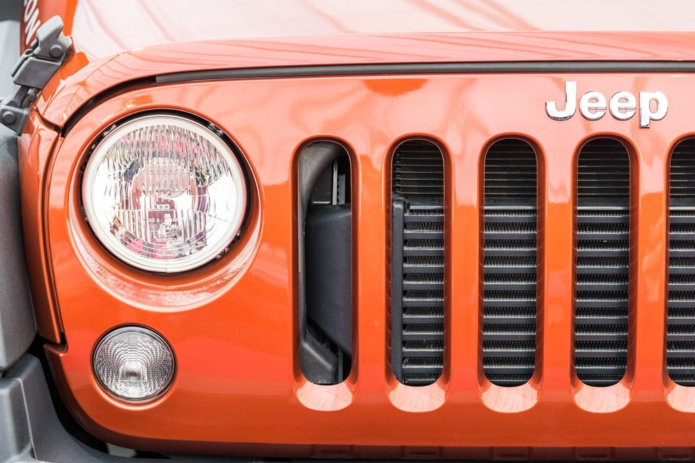 Orange Jeep Wrangler parked on a rocky mountain terrain.