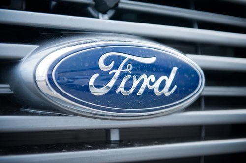 Close-up of a blue and silver Ford oval logo on the front grille of a vehicle.