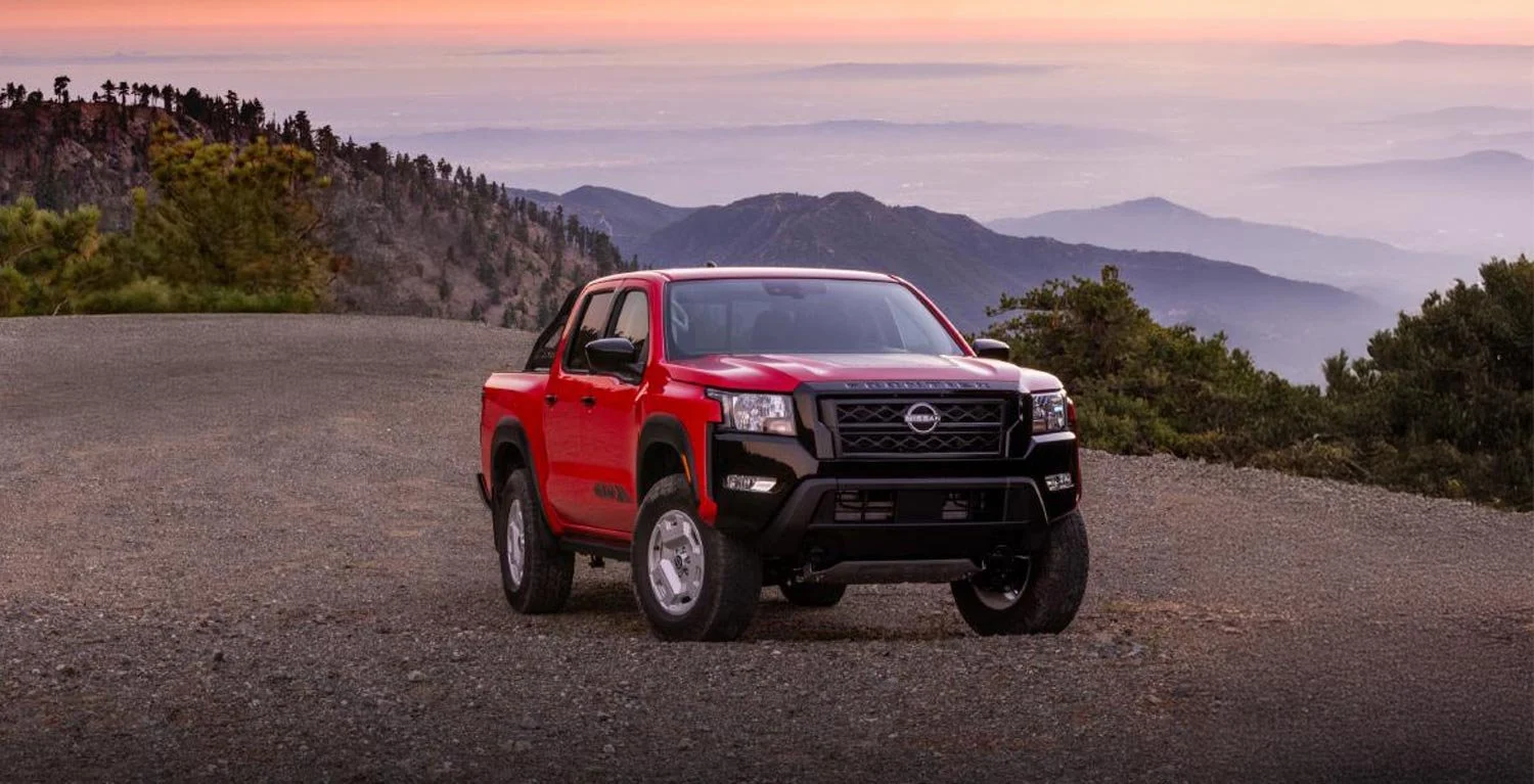 Red pickup truck parked on rocky terrain at sunset