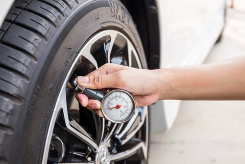 checks the tire pressure of a car with a gauge.