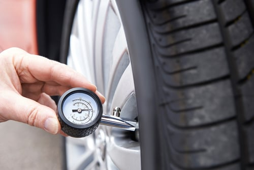 Checking car tire pressure with gauge.