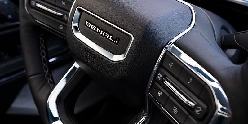 Close-up of a black leather steering wheel featuring the Denali logo.