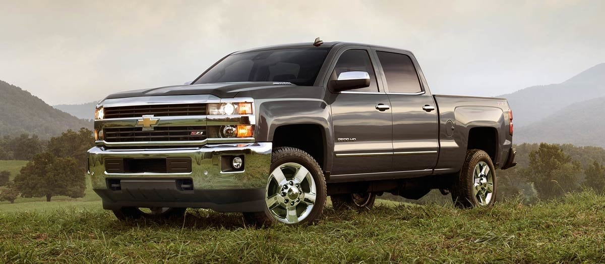 Gray Chevrolet pickup truck parked on rocky desert terrain under a blue sky.