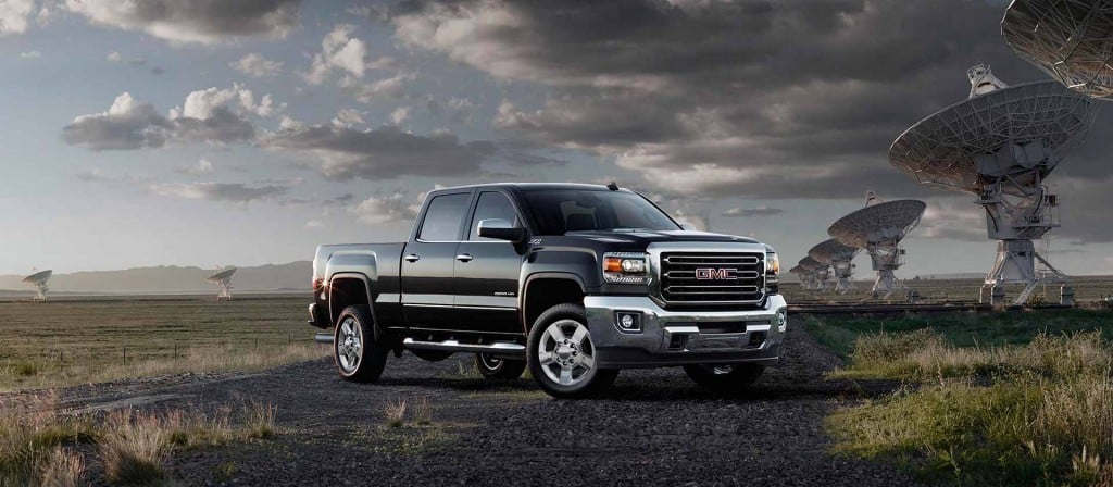 A black GMC AT4X pickup truck pulls a black enclosed trailer through a desert landscape.