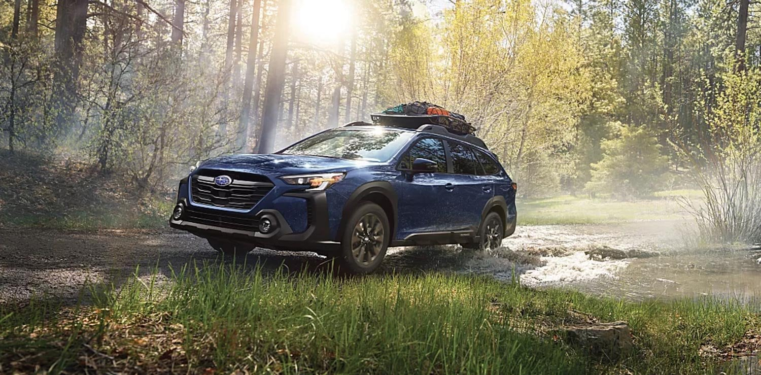 Red Subaru Outback driving on mountain road.