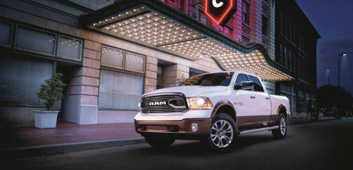 Front view of a White Ram pickup truck parked on a roadside with headlights illuminated