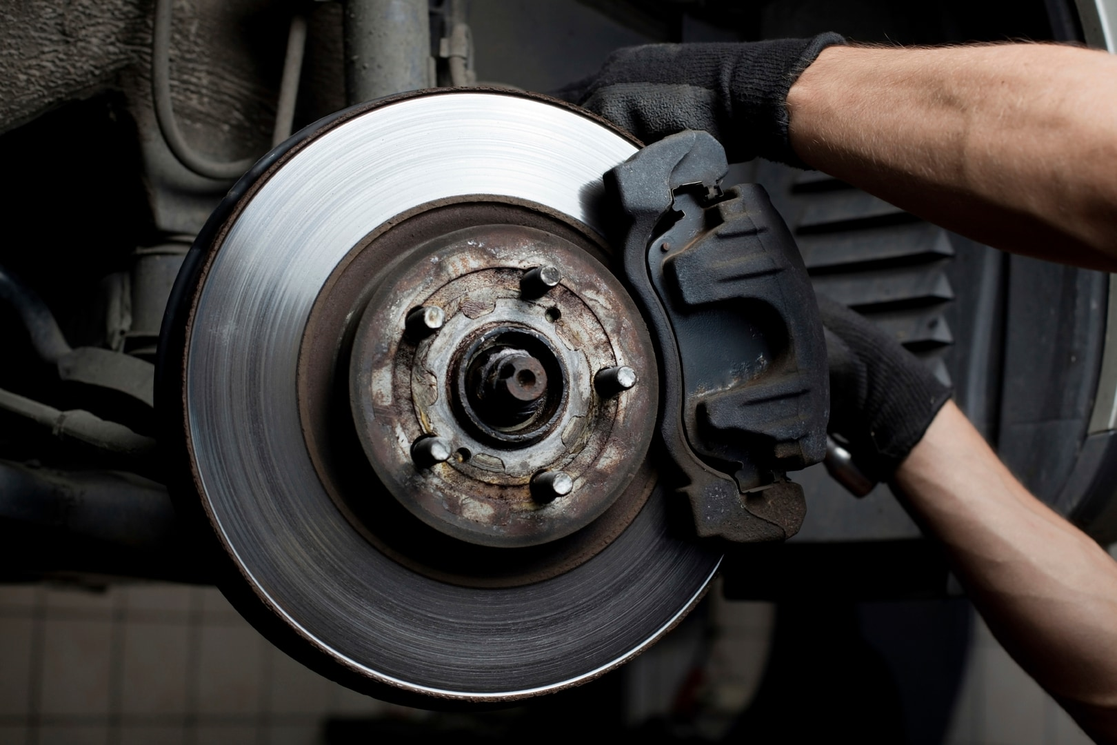 Close-up of a car's disc brake, caliper, and suspension components, seen from below.