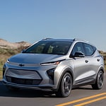 Gray 2024 Chevrolet Equinox EV driving on a city street.