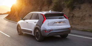 A 2024 Kia Niro EV driving around a bend at sunset near Orangeburg, South Carolina