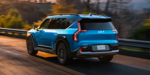A 2025 Kia EV9 driving down a wooded highway near Orangeburg, South Carolina