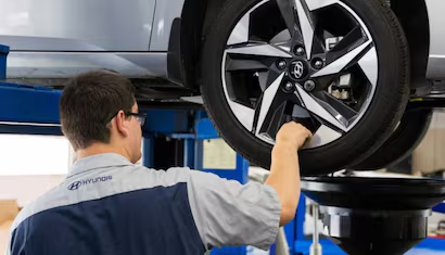 Hyundai technician inspecting tire tread depth at McCarthy Hyundai of Lawrence KS 
