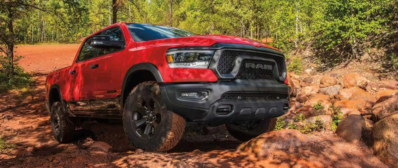Red pickup truck on dust on a dirt road.
