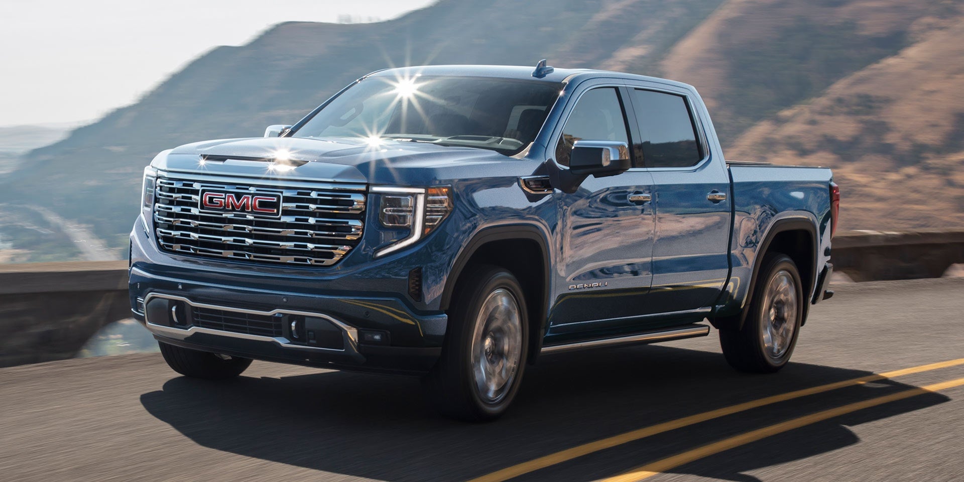Dark blue 2026 GMC Sierra 1500 driving down a road.