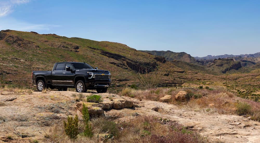 Black 2026 Chevy Silverado 2500 HD parked off-road on a hill.