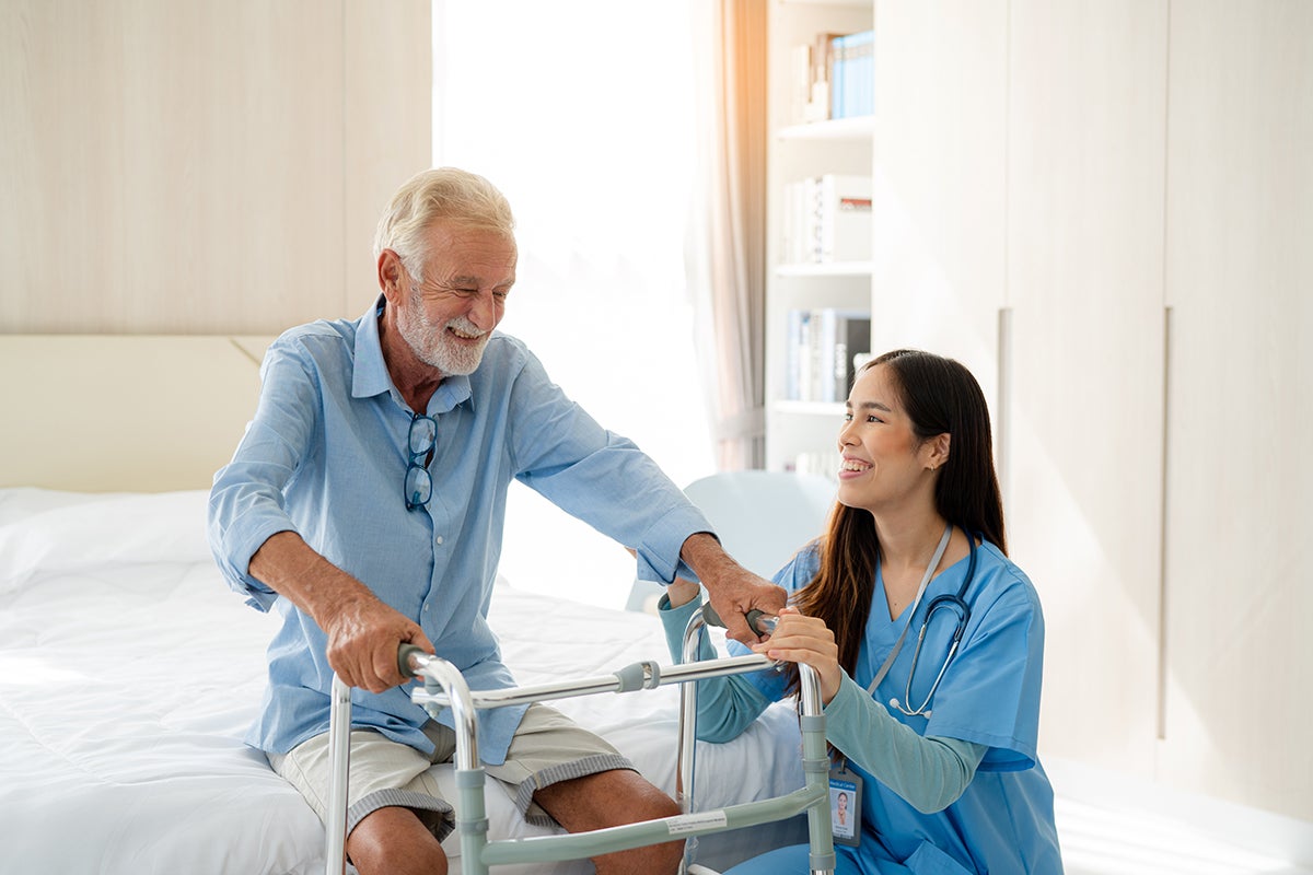 a healthcare provider helping an older gentleman out of bed